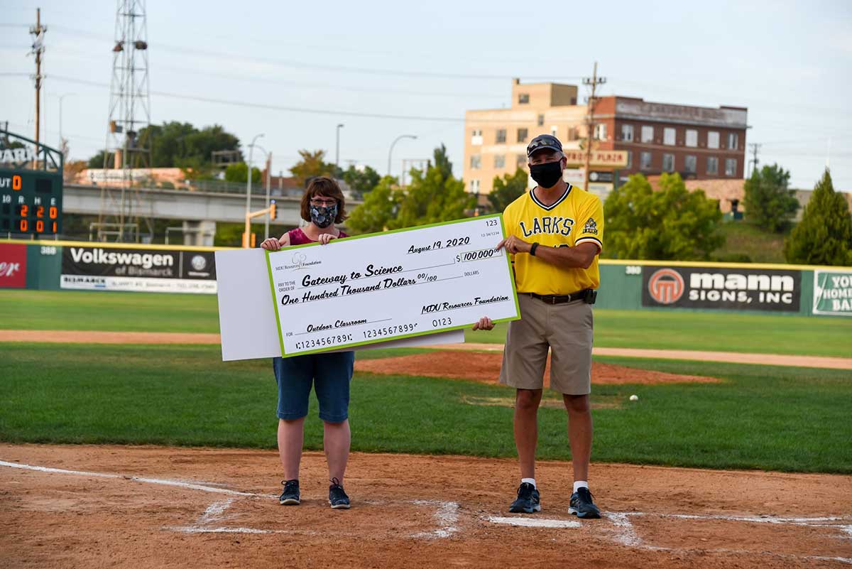 People at a baseball game with a large check