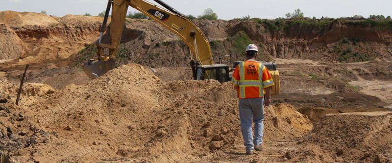 Employee walking toward backhoe