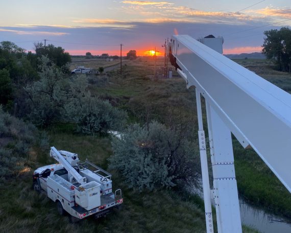 Infrastructure is our business Photo from bucket truck raised above another bucket truck, facing a colorful sunset
